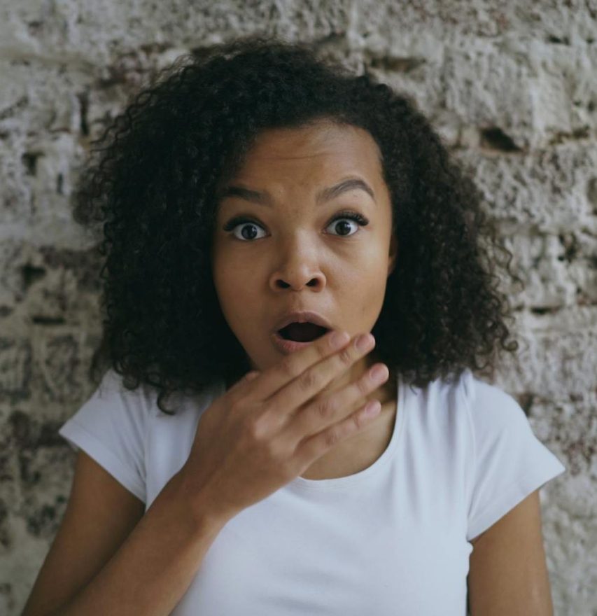 surprised woman against rustic brick wall